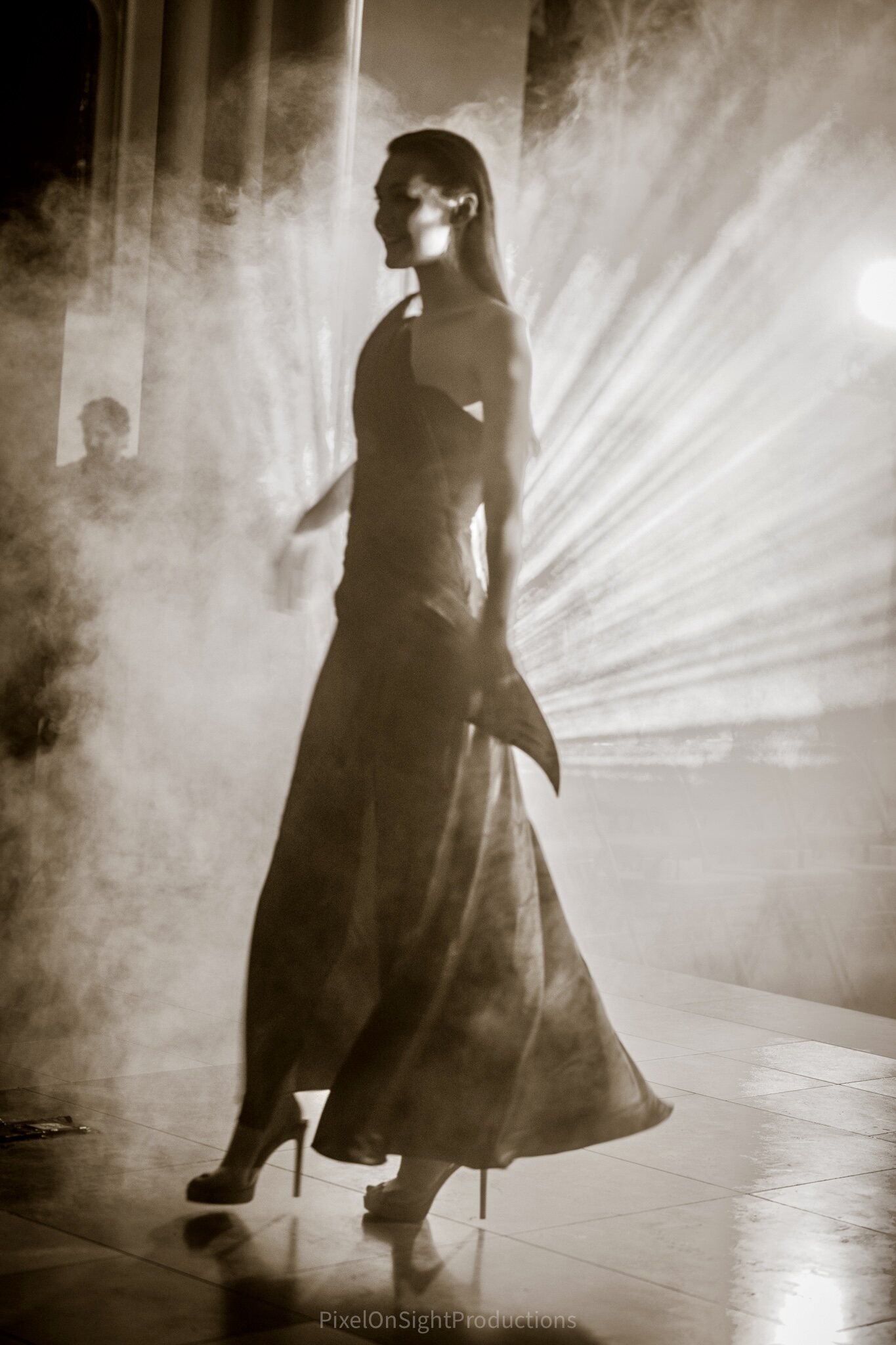 Model moving through theatrical light and smoke